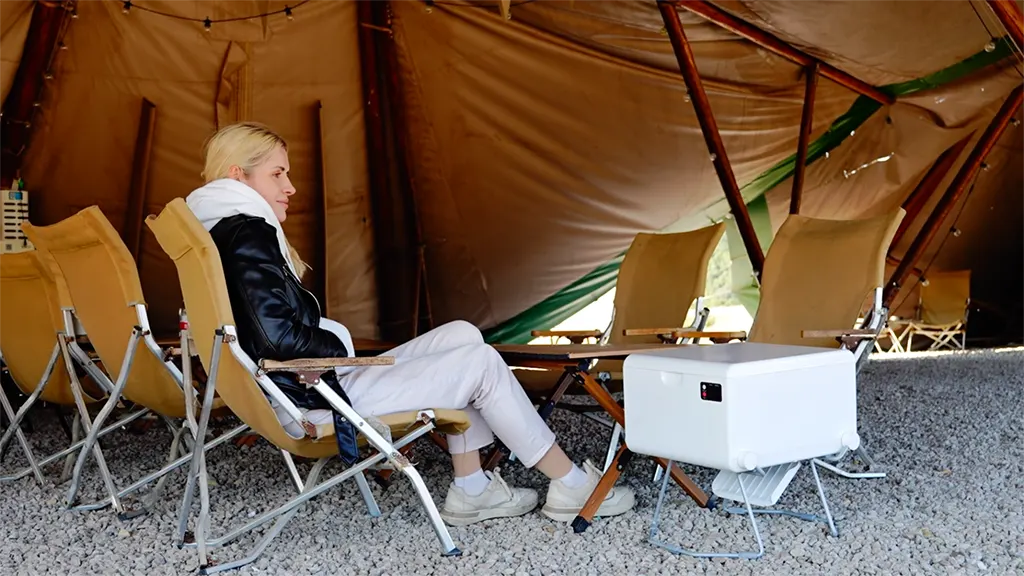 A dry flush camping toilet is placed next to a woman
